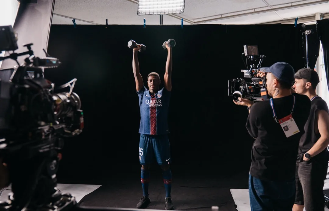 A PSG player pressing dumbbells overhead on camera during the challenge shoot
